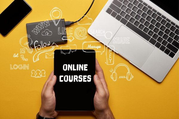 cropped view of man holding digital tablet with online courses illustration